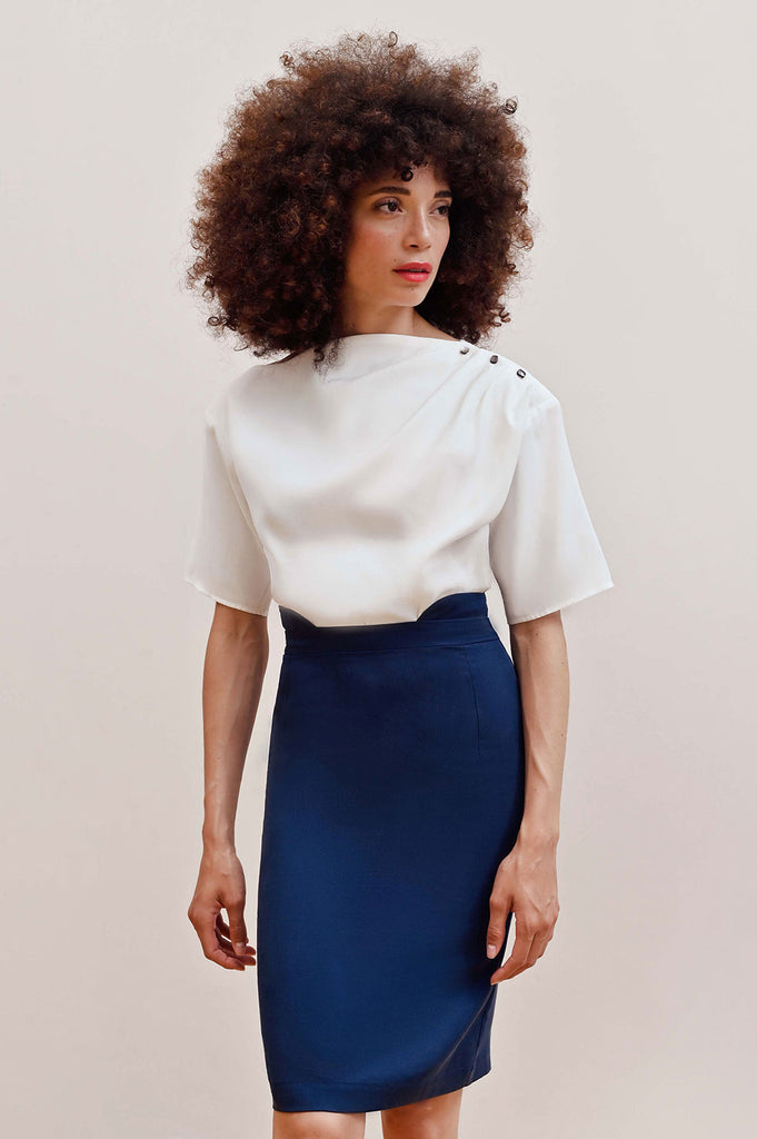 Model wearing a formal white cupro top with Mother of Pearl buttons paired with a navy Tencel pencil skirt.